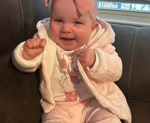 Baby girl wearing pink Minnie Mouse outfit and large pink bow.