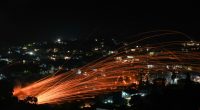 Fiery streaks of handmade rockets light up the night sky over a village during an Easter celebration.