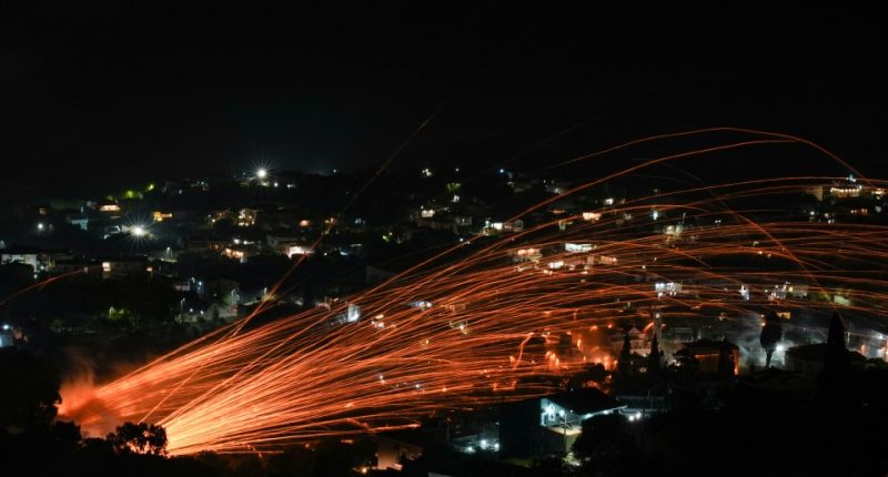 Fiery streaks of handmade rockets light up the night sky over a village during an Easter celebration.