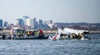 Wreckage of a plane and helicopter in the Potomac River with rescue boats.