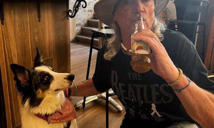 Man with dog drinking beer at a pub.