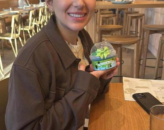 Woman holding a small container with a green bow.
