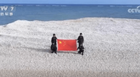 People holding Chinese flag on a small sandbank.
