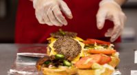 A Five Guys employee assembling burgers.