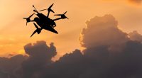Silhouette of a drone flying in a sunset sky.
