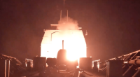 Ship launching a missile at night.