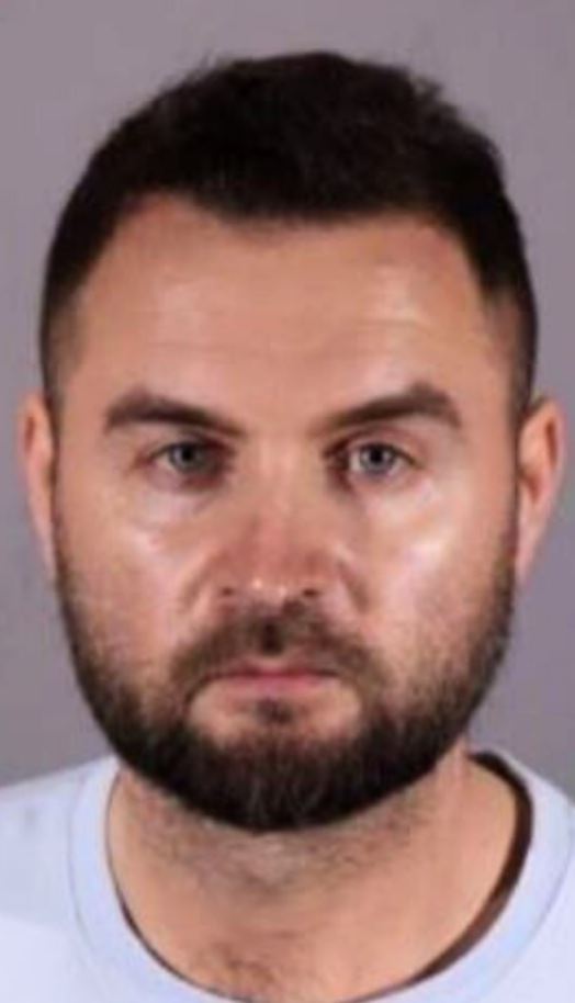 Mugshot of a man with short brown hair and a beard.