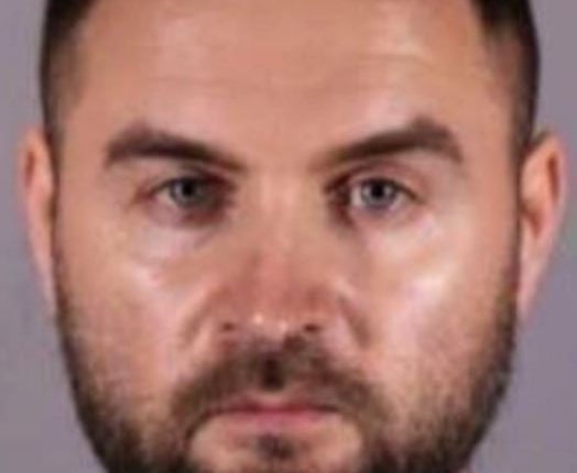 Mugshot of a man with short brown hair and a beard.