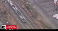 Aerial view of a train stopped on the tracks with several people standing nearby.