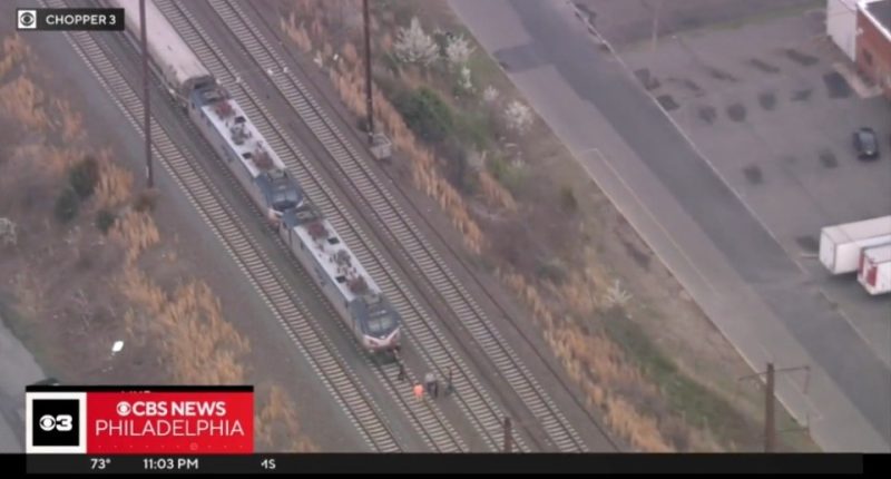 Aerial view of a train stopped on the tracks with several people standing nearby.