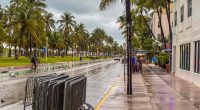 Rain-soaked Ocean Avenue in Miami Beach with few people present.