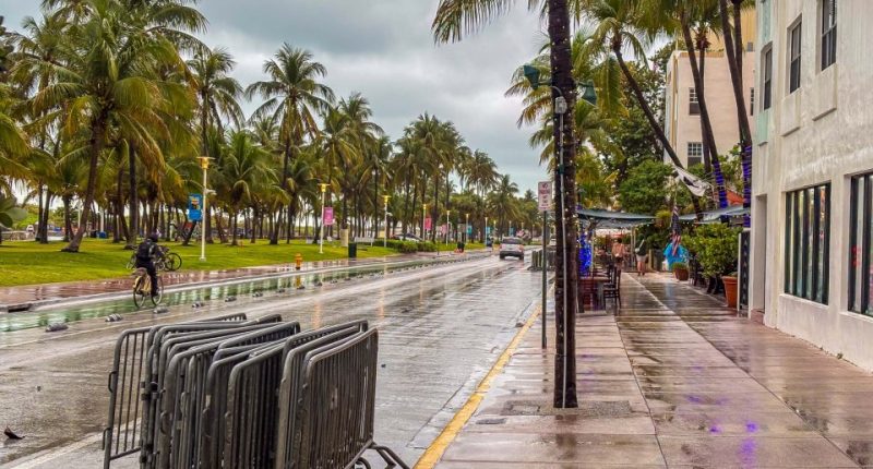 Rain-soaked Ocean Avenue in Miami Beach with few people present.