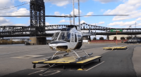Helicopter on a landing pad with a bridge in the background.