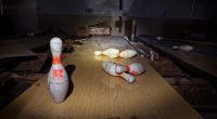 Abandoned bowling alley with several bowling pins on the lane.