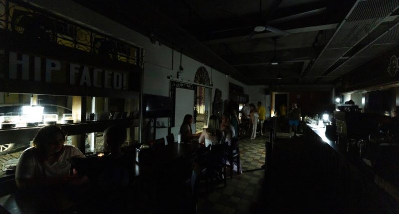 Patrons dining in a dimly lit restaurant during a power outage.