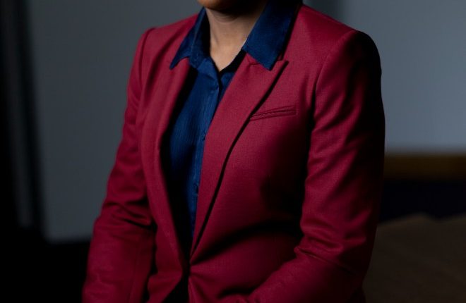 Portrait of Kemi Badenoch in a red suit.