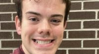 Photo of a young man smiling and giving a peace sign.