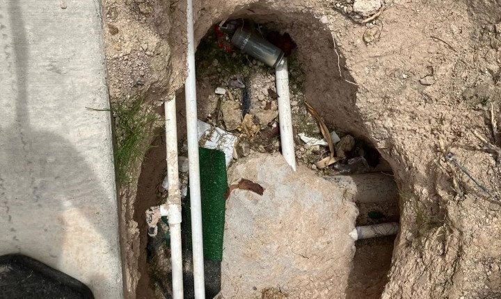 Exposed pipes and a valve in a dug-up area of ground.