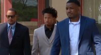 Three men in suits walking outside a courthouse.