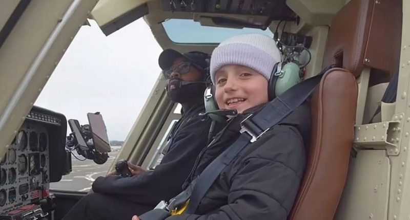 A child sits in a helicopter next to the pilot.