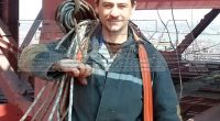 Worker carrying rope on a construction site.