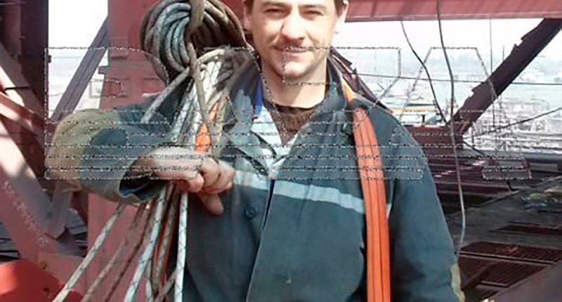Worker carrying rope on a construction site.