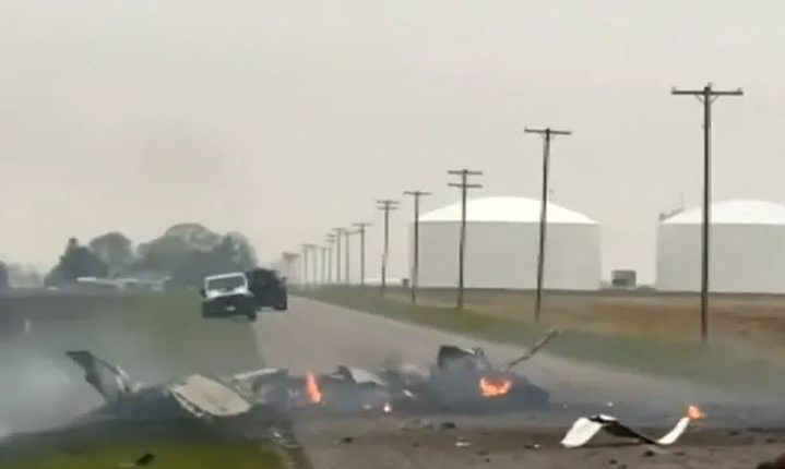 Plane crash on a road near some storage tanks.