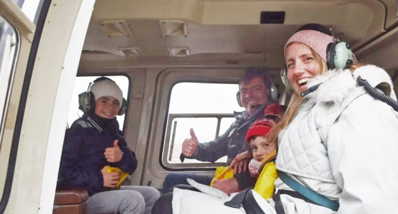Family of five giving thumbs up inside a helicopter.
