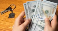 Hands counting money and house keys.