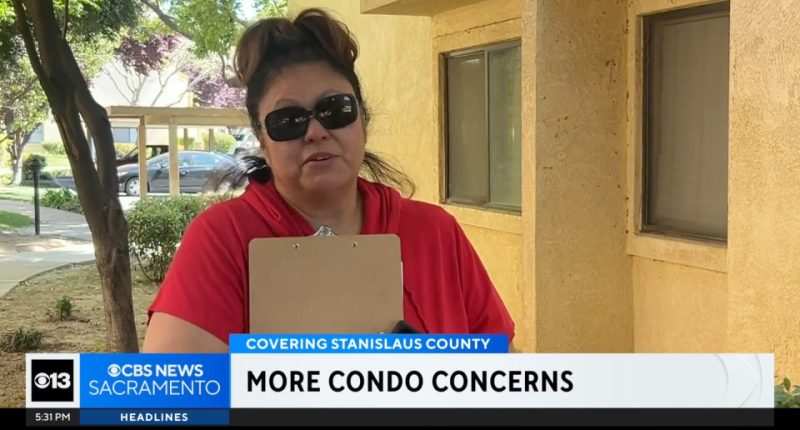 Woman in red shirt holding clipboard discusses condo concerns.