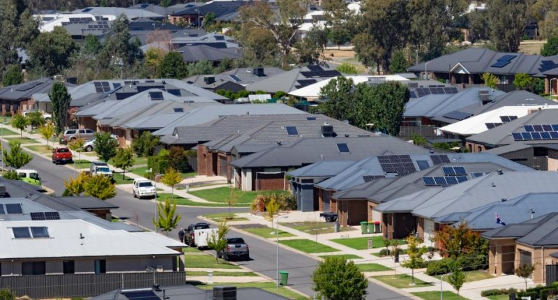 Aerial view of a suburban neighborhood with houses equipped with solar panels.