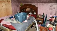 Messy bedroom with a bed, dresser, and various items strewn about.