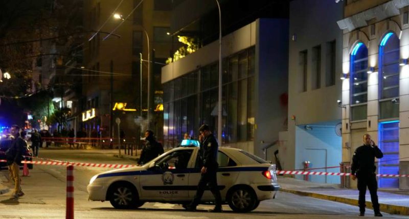 Police officers close a road following a suspected bomb explosion near Hellenic Train offices in Athens.