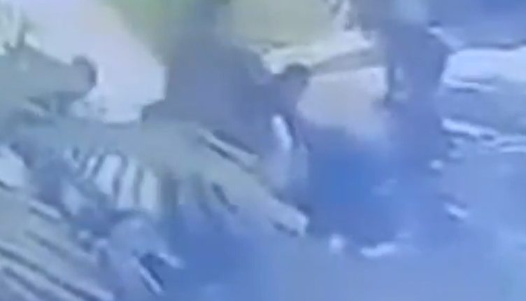 Blurry security camera footage of people outside.