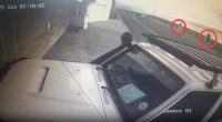 Security camera footage of a vehicle with two people visible in the distance.