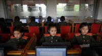 North Korean female students in uniform using laptops in a classroom.