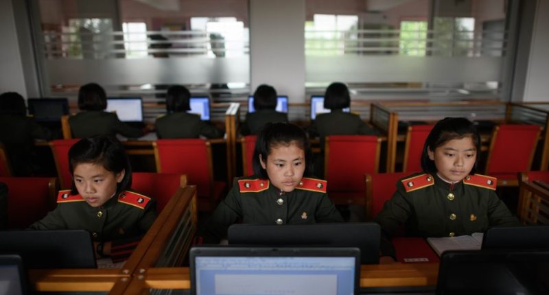 North Korean female students in uniform using laptops in a classroom.