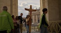 A faithful carries a cross in St. Peter's Square at the Vatican, Friday, March 7, 2025. (AP Photo/Francisco Seco)