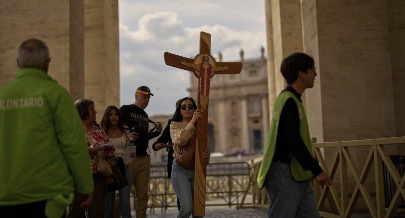 A faithful carries a cross in St. Peter's Square at the Vatican, Friday, March 7, 2025. (AP Photo/Francisco Seco)