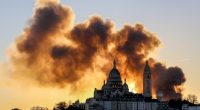 Smoke from a large fire billows behind the Sacré-Cœur Basilica in Paris.