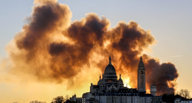 Smoke from a large fire billows behind the Sacré-Cœur Basilica in Paris.