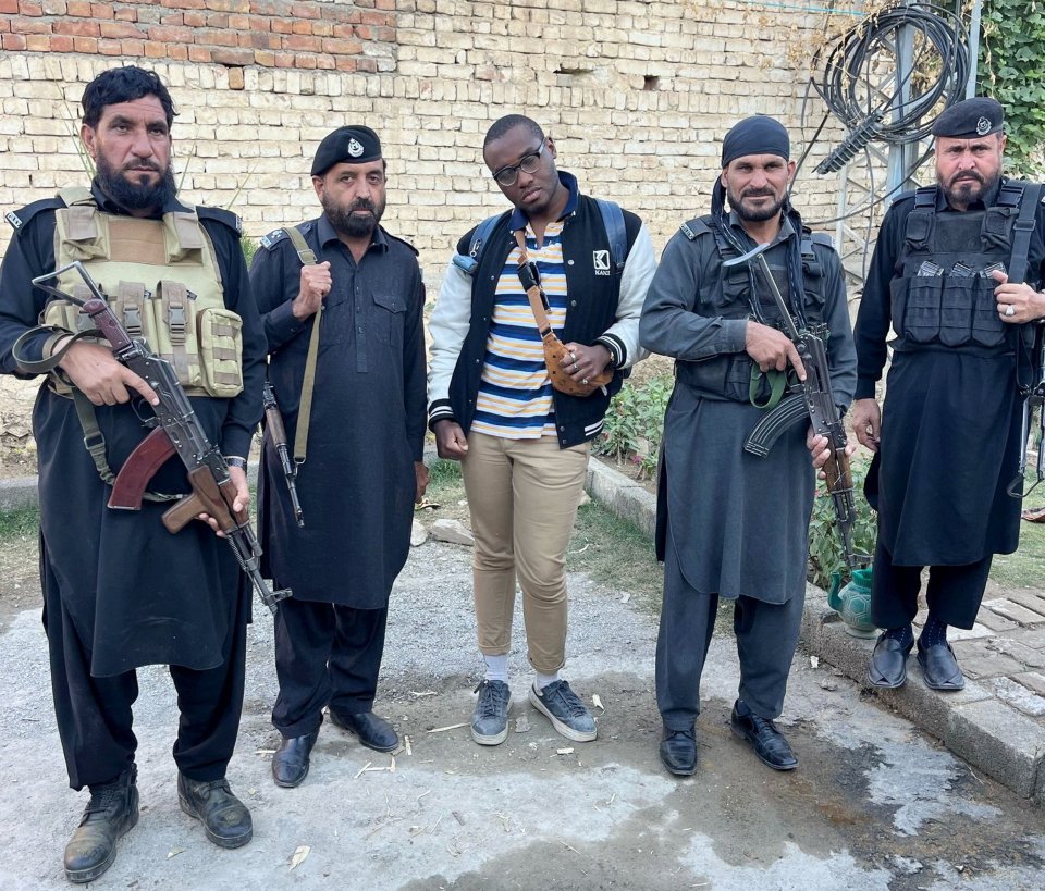 A man stands between four armed guards.