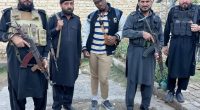 A man stands between four armed guards.