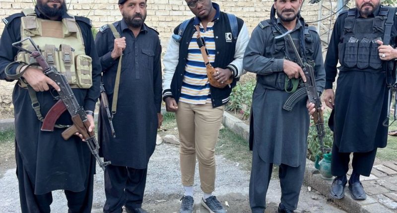 A man stands between four armed guards.