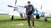 WWII veteran standing in front of a fighter plane.