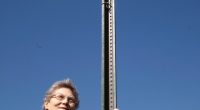 Woman standing by Monowi, Nebraska town sign.