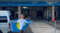 Young man holding Palau flag at Palau International Airport.