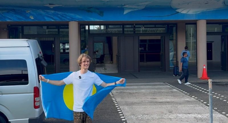 Young man holding Palau flag at Palau International Airport.