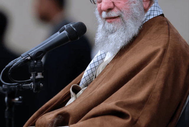 Portrait of Ayatollah Ali Khamenei speaking into a microphone.