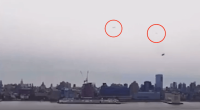 Two unidentified objects in the sky over a city skyline.